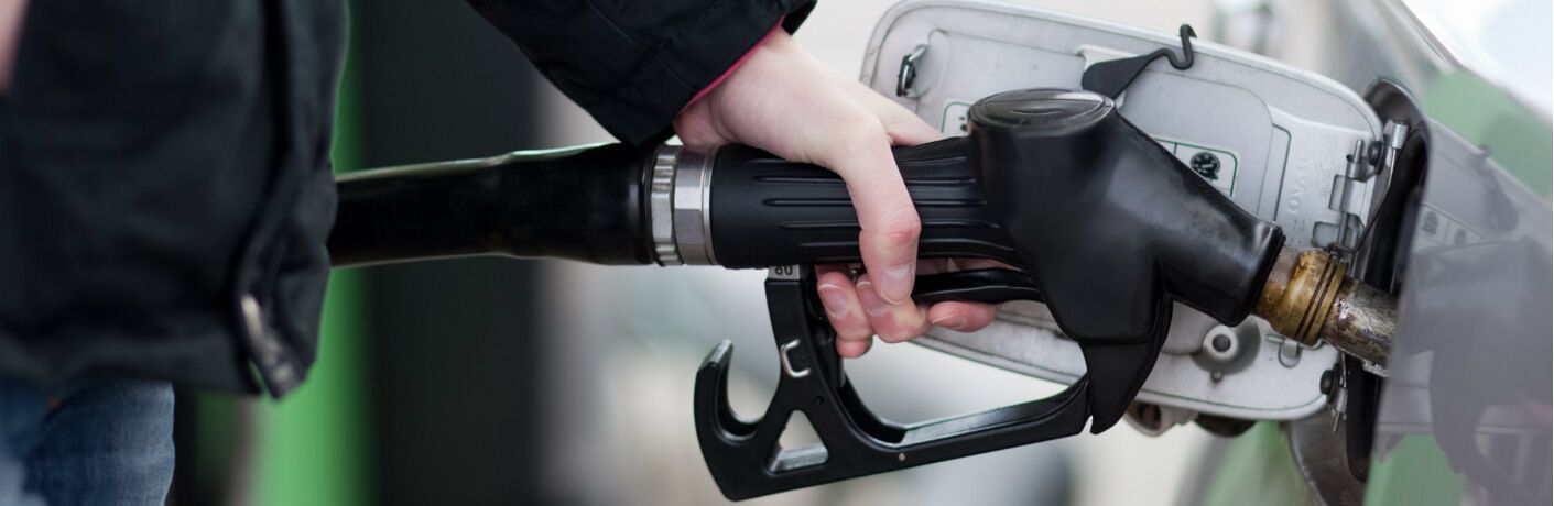 A hand fills up a gas tank on a car.