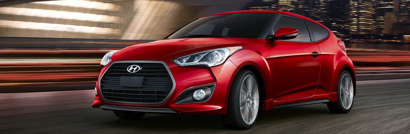 Red Hyundai Veloster with blurred street background