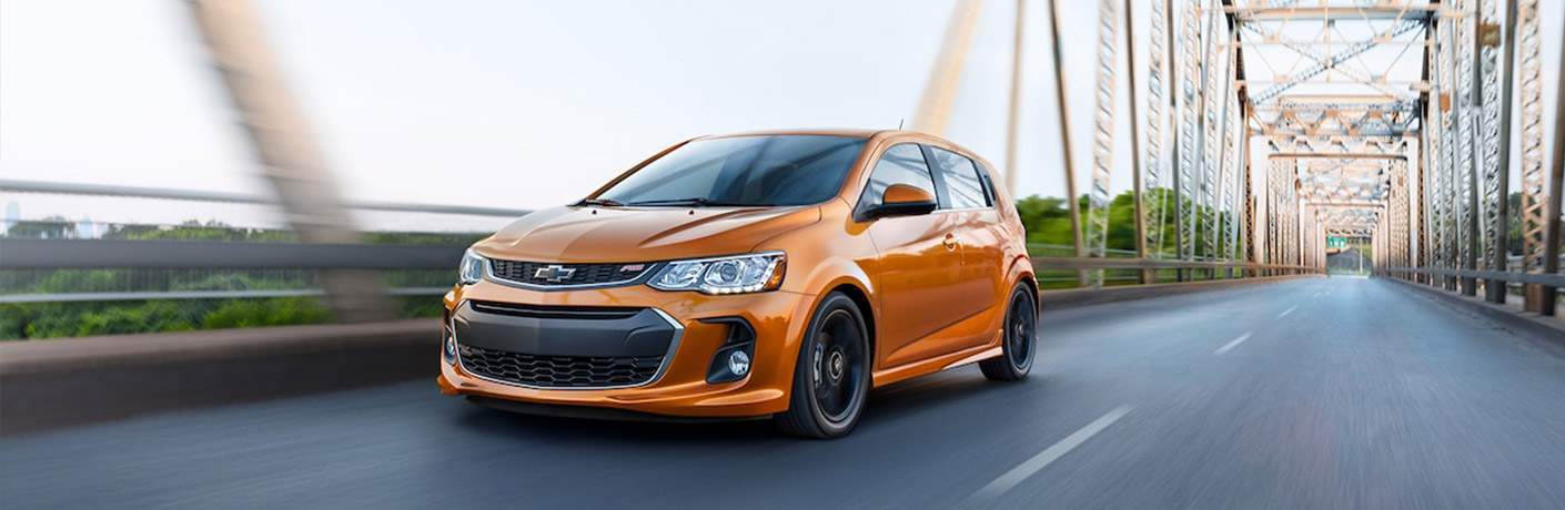 Orange Chevy Sonic driving over a suspension bridge