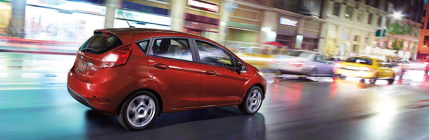 2018 Ford Fiesta in red driving down a busy city street at night