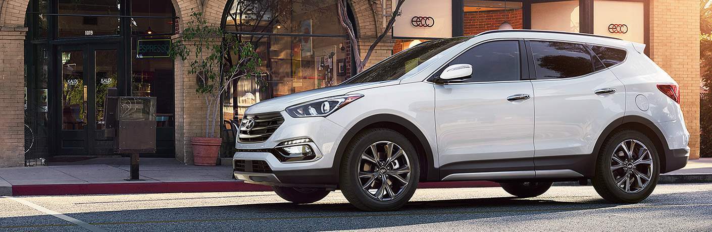 Hyundai Santa Fe in white stopped in front of a city store front