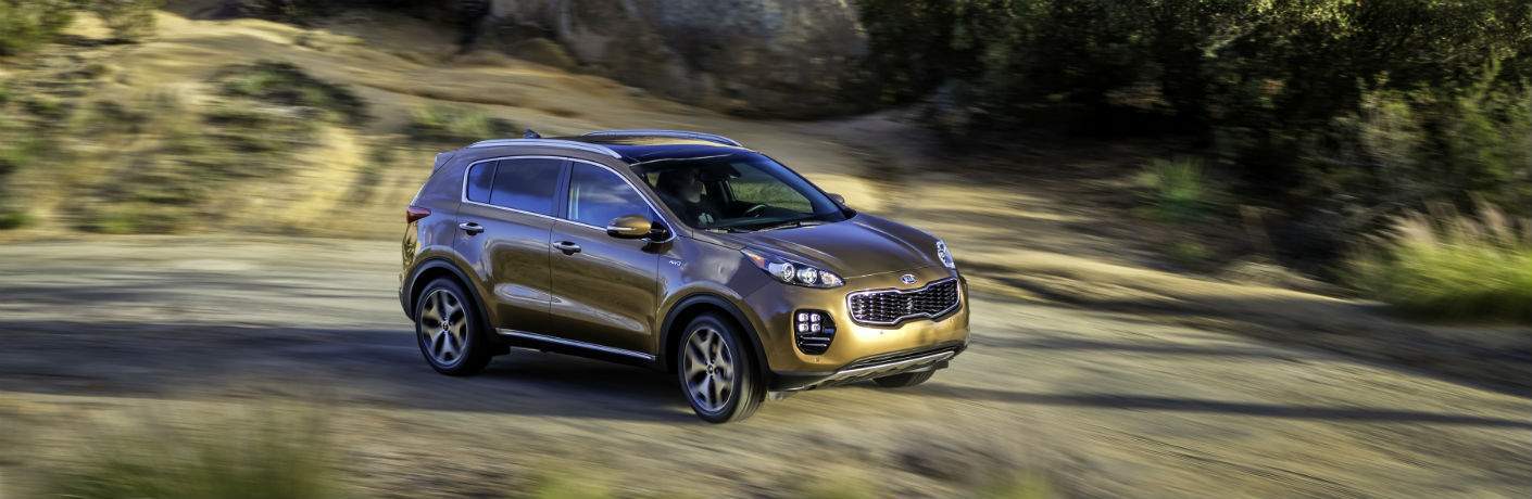 2018 Kia Sportage in gold driving on a trail in nature