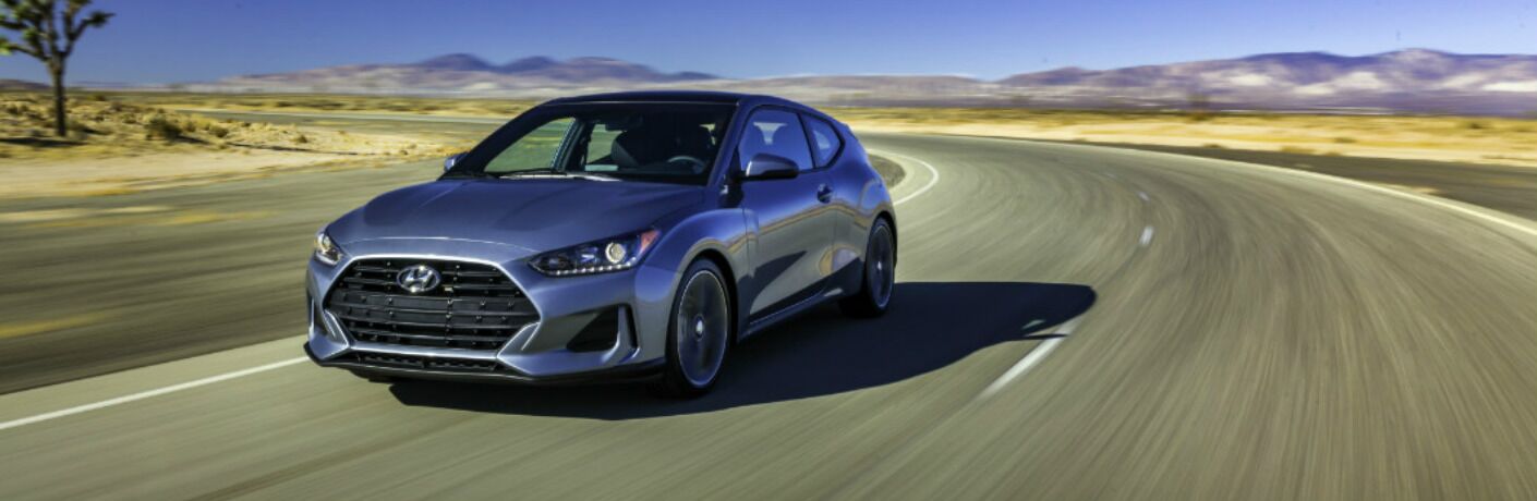 2019 Hyundai Veloster driving around a curve on a desert road