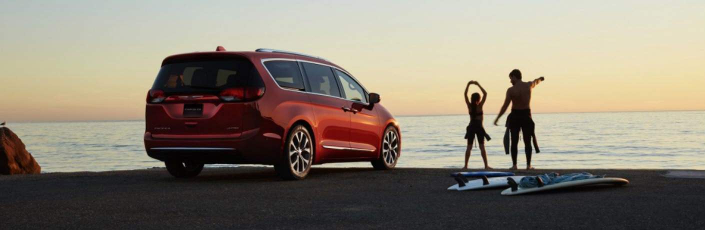 Father and daughter surfing at the beach with the 2018 Chrysler Pacifica in the background