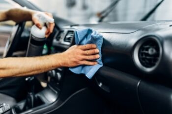 photo of a man cleaning the dashboard of a car with a microfibre rag