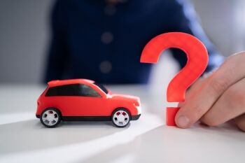 photo of a toy car next to a paper cutout of a question mark