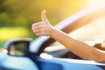 person giving a thumbs up out of a car window