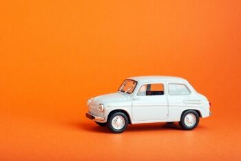a model car of an old vehicle sits in front of an orange background