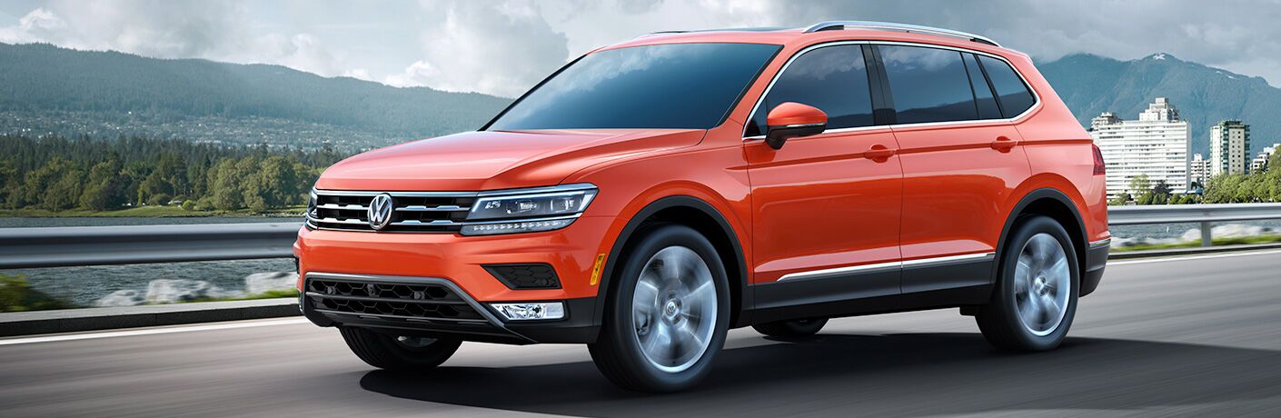 Orange 2018 VW Tiguan driving by a lake