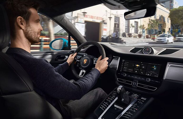 A photo of a person behind the wheel of a 2020 Porsche Macan.