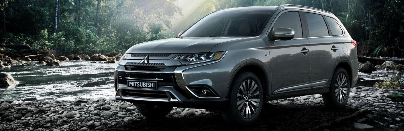 2020 Mitsubishi Outlander slate grey parked on rocks in front of stream