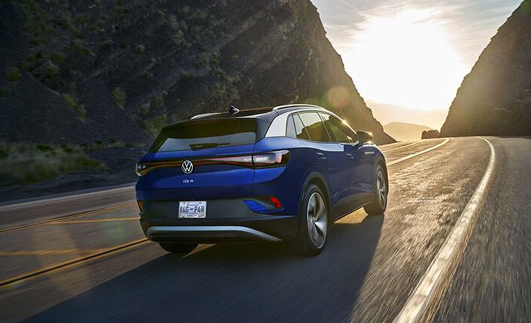 A rear view of an ID.4 in Dusk Blue Metallic, driving along a mountain road.