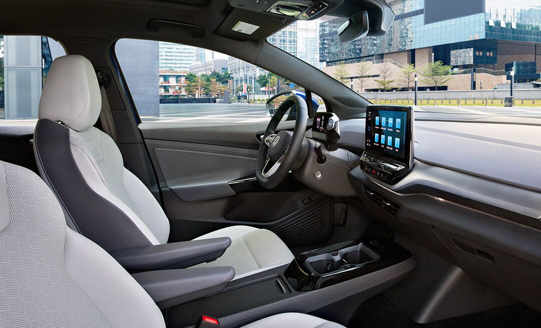 A shot of an ID.4 parked next to rock wall, with focus on the front seats, steering wheel, dash and center console display.