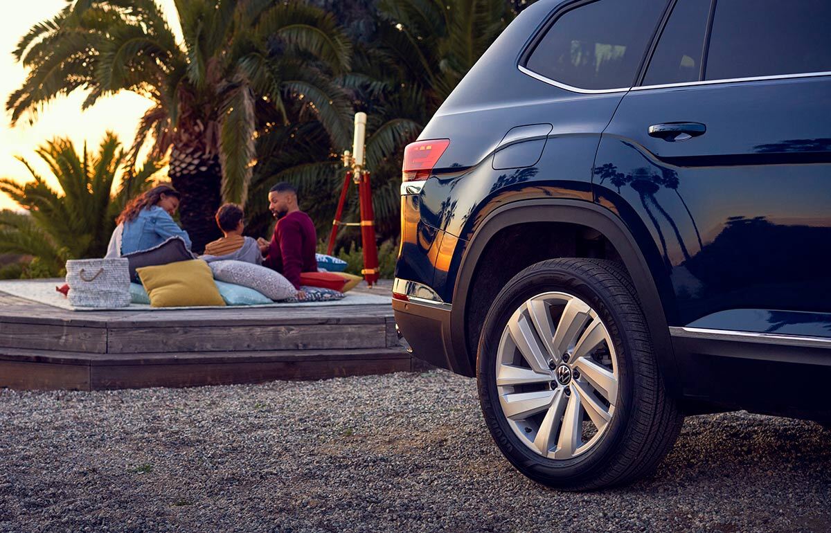 An Atlas is parked with a family enjoying time outside in the background.