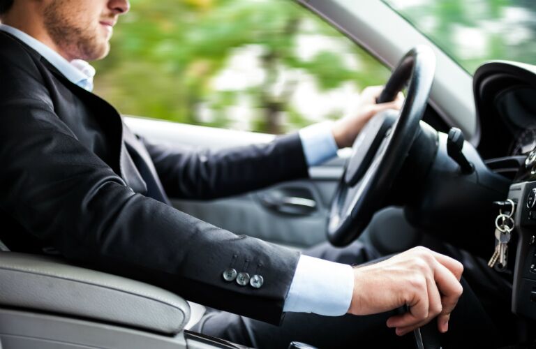 driver driving a manual transmission sedan