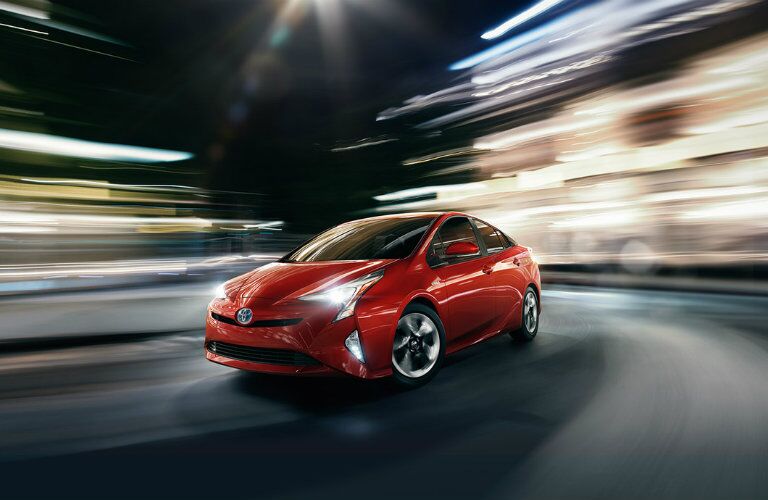 red 2016 Toyota Prius driving in the city