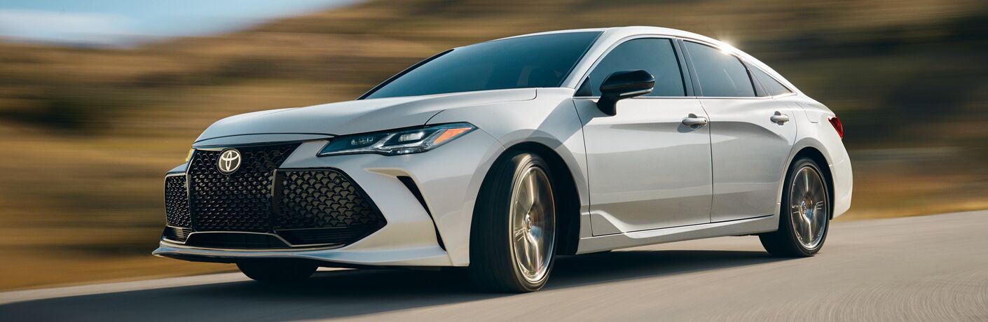 White 2019 Toyota Avalon Hybrid driving on waterfront road