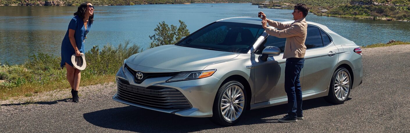 woman getting her picture taken next to the 2019 Toyota Camry Hybrid