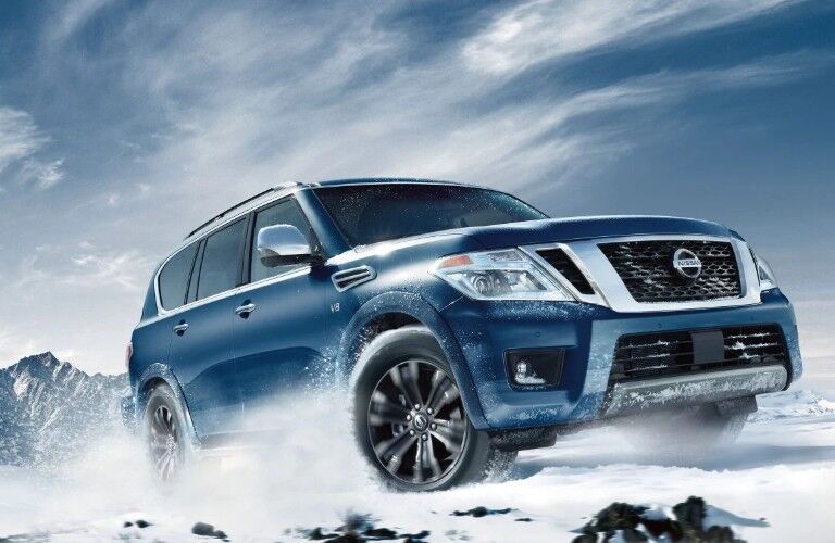 Front passenger angle of a blue 2019 Nissan Armada driving through snow
