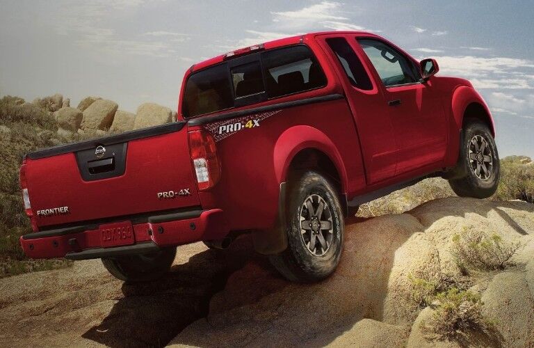 Rear passenger angle of a red 2019 Nissan Frontier on large rocks