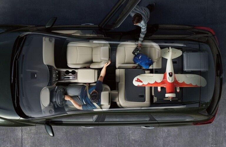 Aerial angle of a black 2019 Nissan Pathfinder showing the third row seats and driver second row seat down with a small airplane using the space.