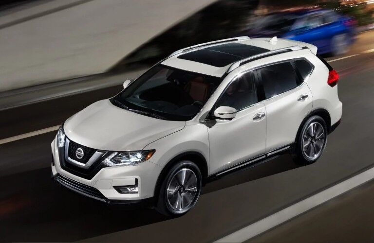 Front driver aerial angle of a white 2019 Nissan Rogue driving on a road