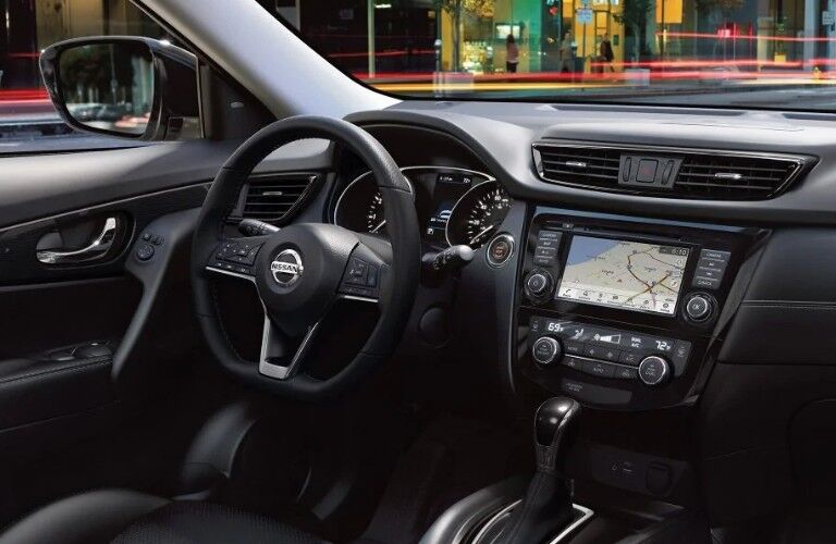 Front passenger angle of the black steering wheel, touchscreen, and dashboard in the 2019 Nissan Rogue