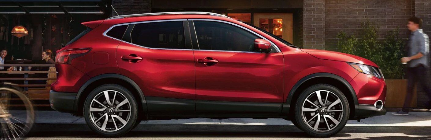 Passenger angle of a red 2019 Nissan Rogue Sport parked on the side of a street