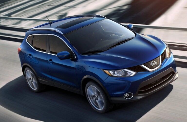 Front passenger angle of a blue 2019 Nissan Rogue Sport driving down a road