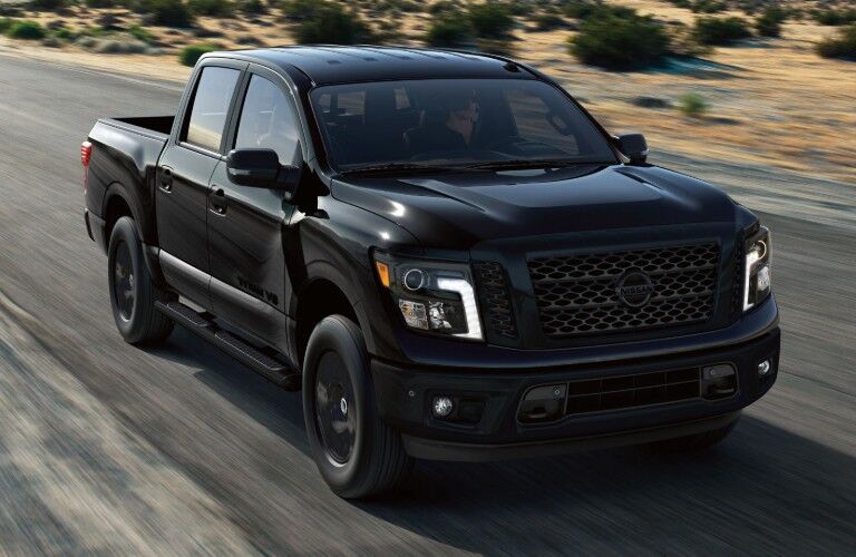 Front passenger angle of a black 2019 Nissan TITAN driving down a road