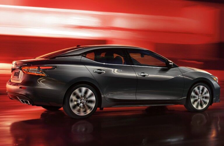 Passenger angle of a black 2020 Nissan Maxima on a blurry red background