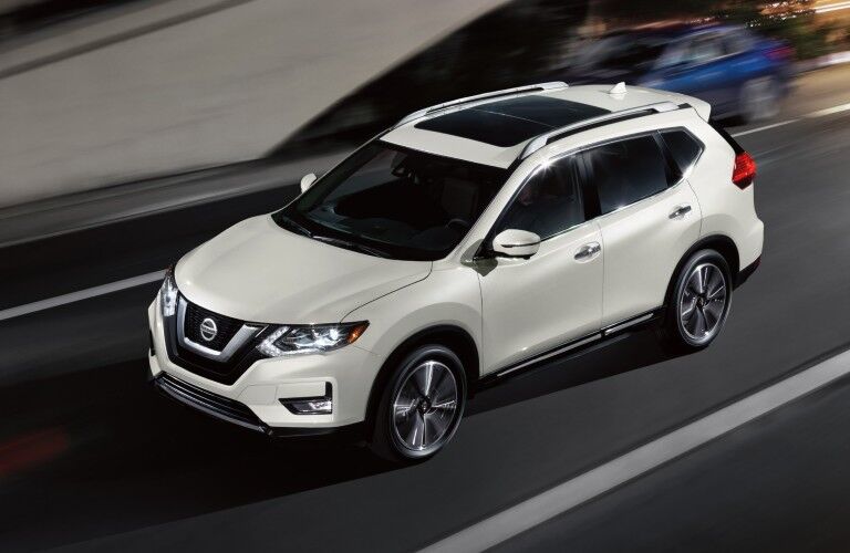 Front driver angle of a white 2020 Nissan Rogue driving down a road