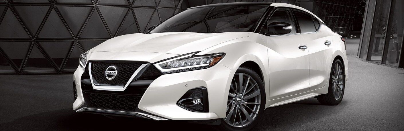 Front driver angle of a white 2020 Nissan Maxima on a dark background