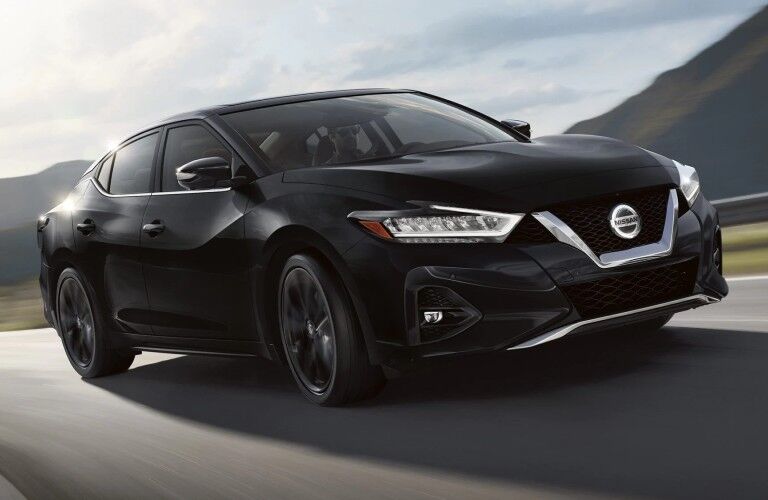 Front passenger angle of a black 2020 Nissan Maxima SR driving down a road