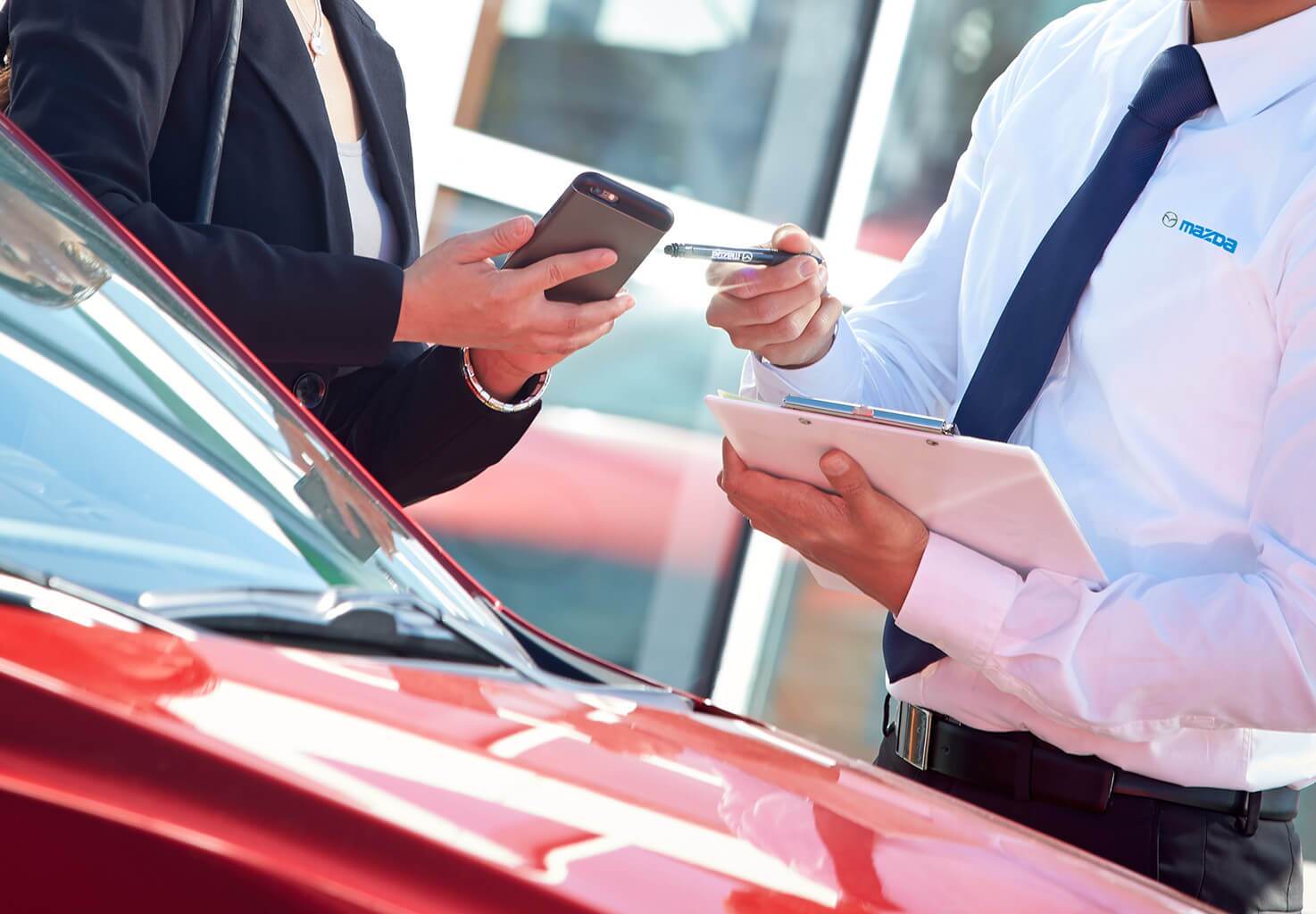 Salesman and customer discussing deal over a car
