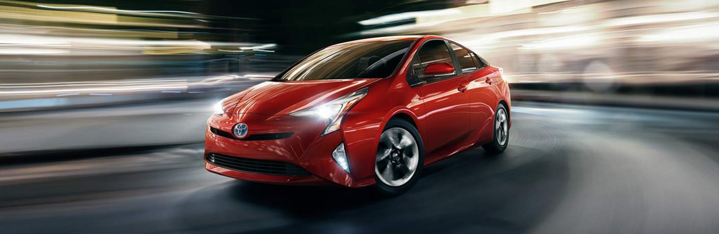 red 2018 Toyota Prius driving around corner with blurred background