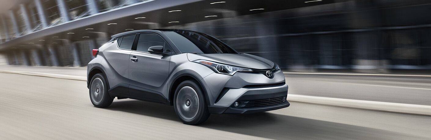 silver and black 2019 Toyota C-HR driving down urban street