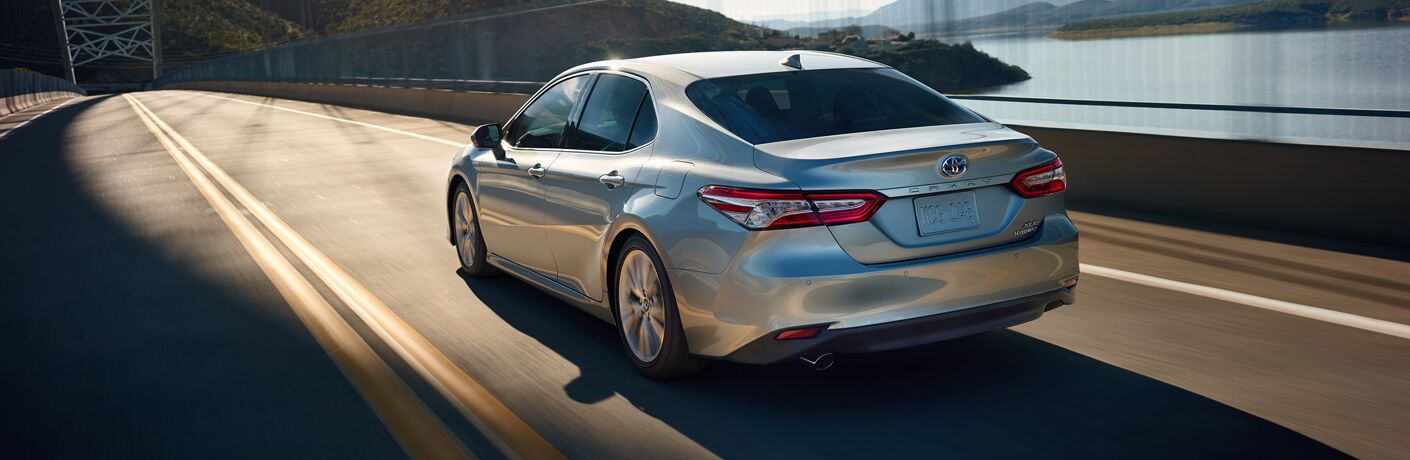 Silver 2019 Toyota Camry Hybrid driving on a bridge