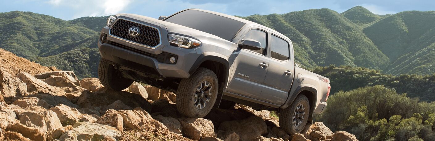 gray 2019 Toyota Tacoma driving up rocky off-road terrain