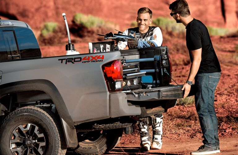 Two men standing by the tailgate of a grey 2019 Toyota Tacoma