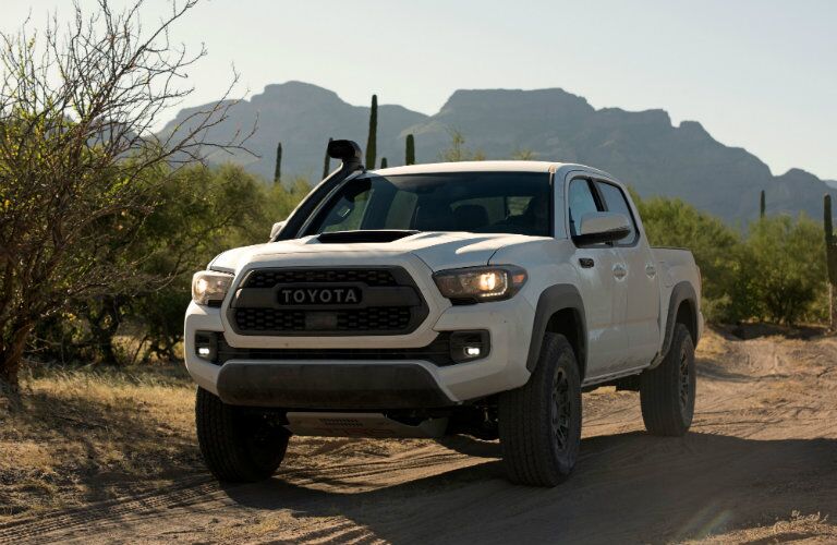 front side view of white 2018 Toyota Tacoma TRD Pro in the desert backed by mountains
