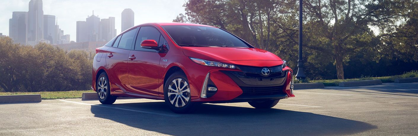 Red 2020 Toyota Prius Prime with a city skyline in the background