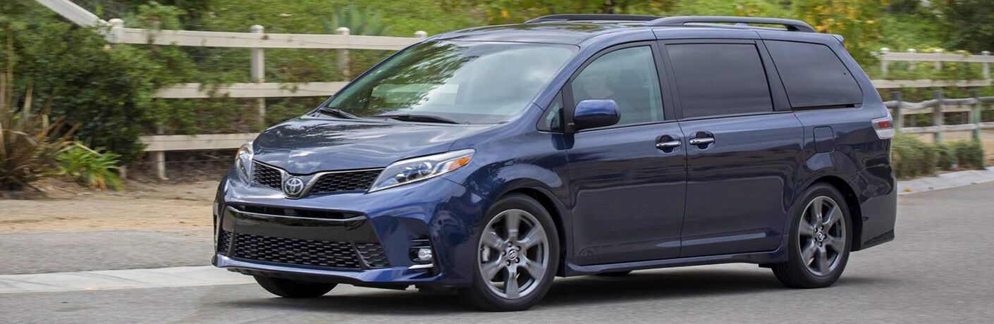 Blue 2020 Toyota Sienna driving by a wood fence