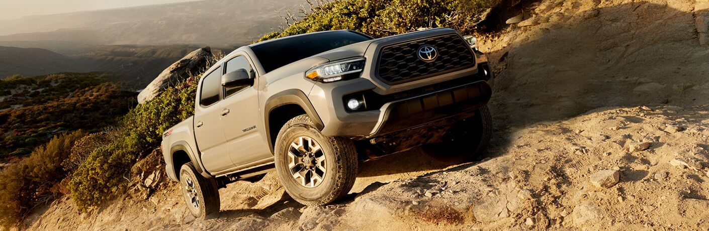 tan 2020 Toyota Tacoma driving up steep, rocky incline