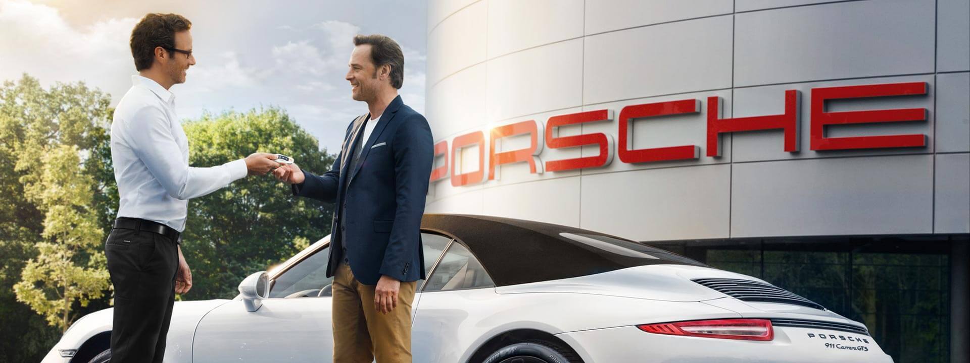 Two men exchanging Porsche keys in