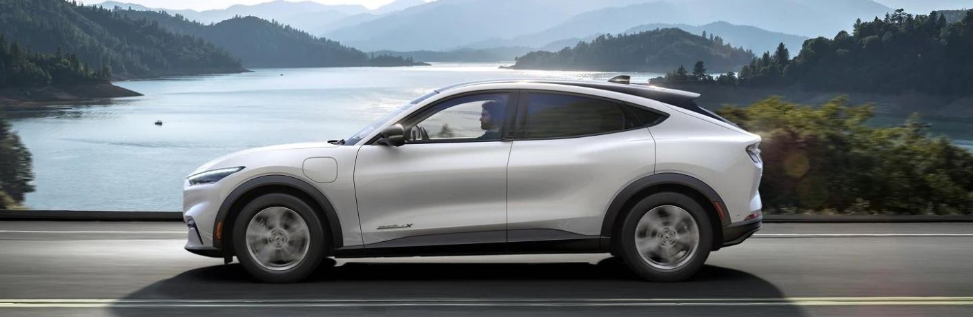 Side view of a man driving the 2023 Ford Mustang MACH-E® through a bridge.