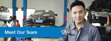 Man in car shop looking at camera with car in background and "Meet our Team" text