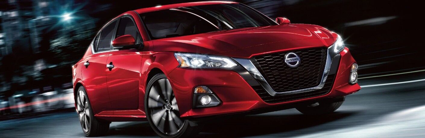 Front passenger angle of a red 2020 Nissan Altima driving at night