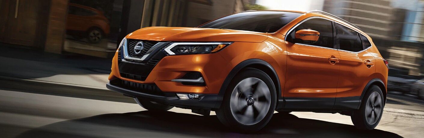 Front driver angle of an orange 2020 Nissan Rogue Sport driving in a city
