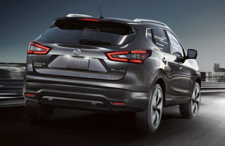 Rear passenger angle of a grey 2020 Nissan Rogue Sport driving on a road